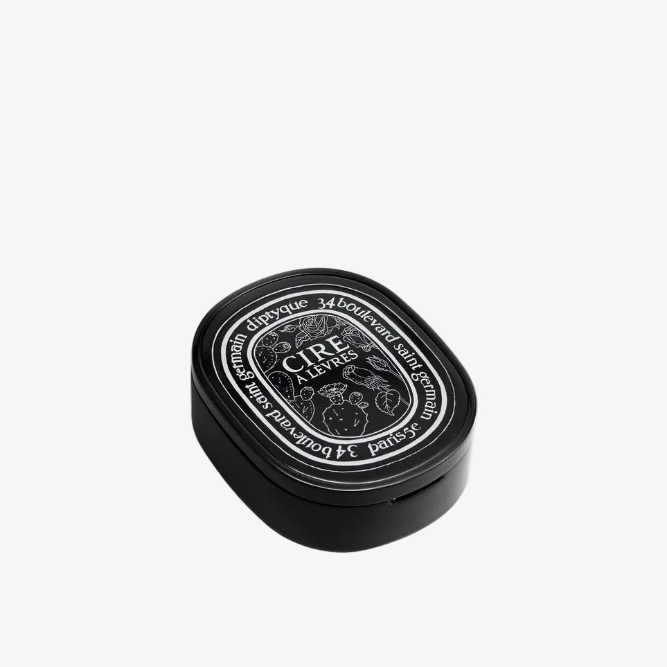 A small black oval tin with a white printed label reading 'CIRE PARFUMÉE' and 'DIPTYQUE', photographed on a clean white background.