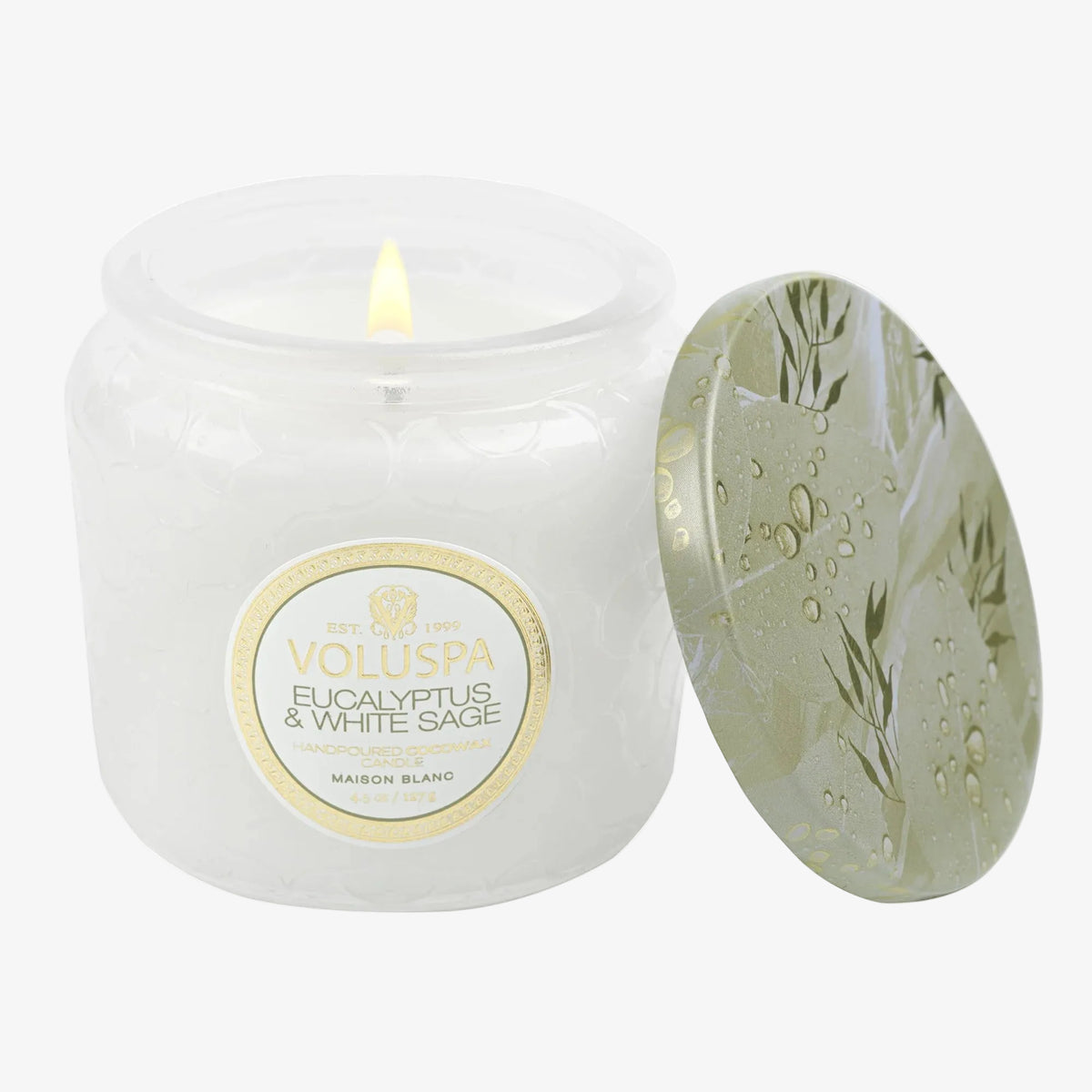 Volluspa candle with a lit wick and decorative lid on a white background