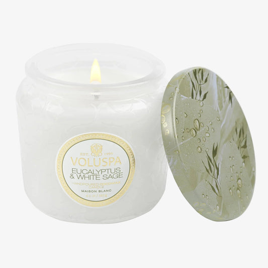 Volluspa candle with a lit wick and decorative lid on a white background